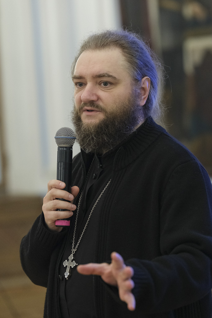 Крупный план архимандрита Саввы (Мажуко), держащего микрофон и жестикулирующего рукой