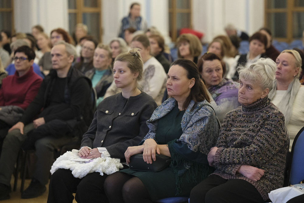 Группа женщин внимательно слушает выступление, сидя в зале