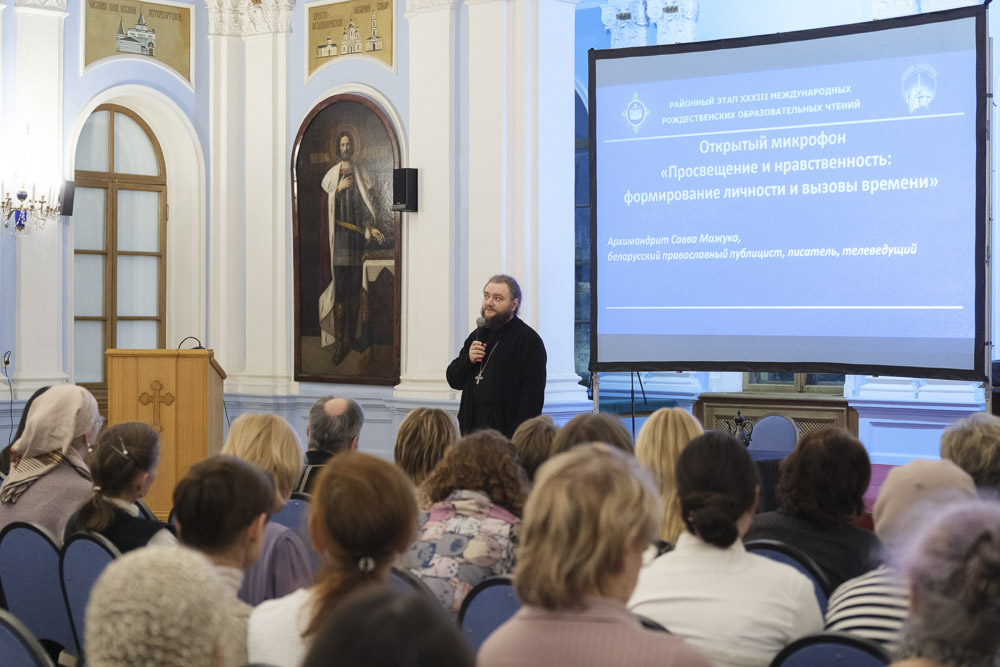 Архимандрит Савва (Мажуко) выступает на фоне большого экрана с презентацией и иконы