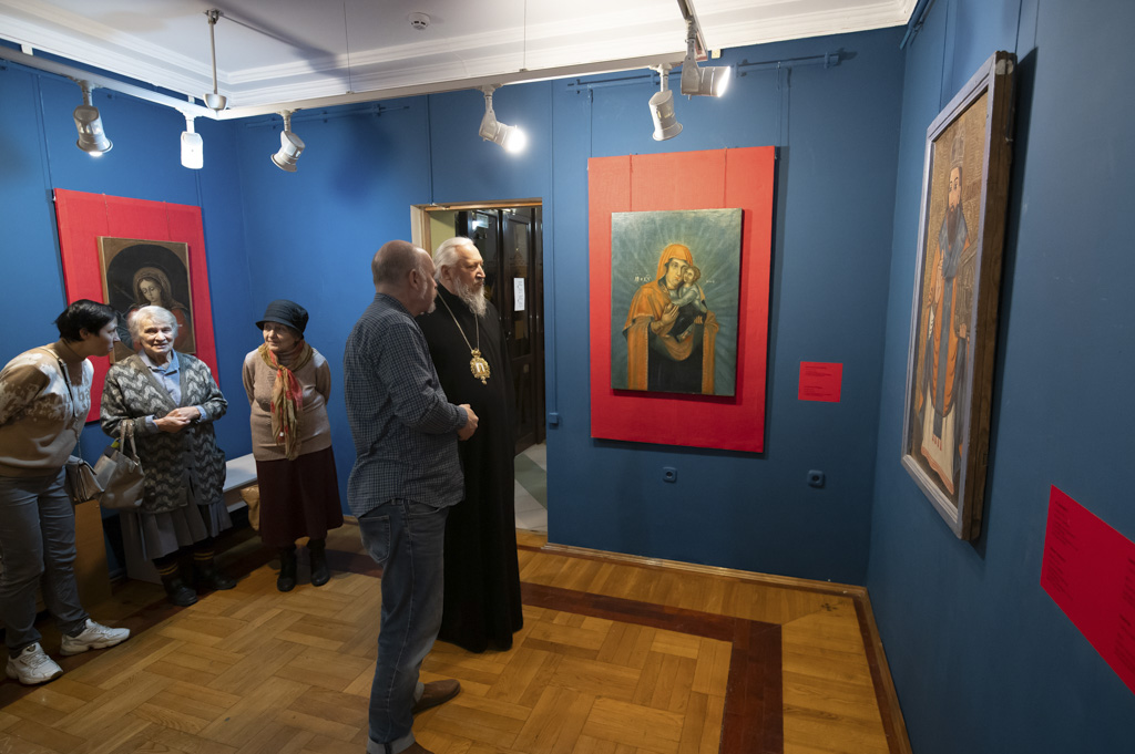 Экскурсовод беседует со священником и пожилыми посетительницами возле иконы в красном киоте